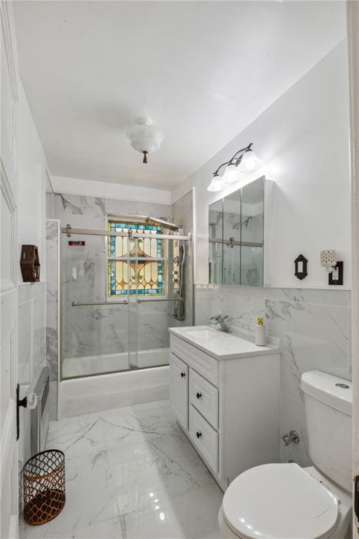 bathroom featuring toilet, tile walls, marble finish floor, and vanity
