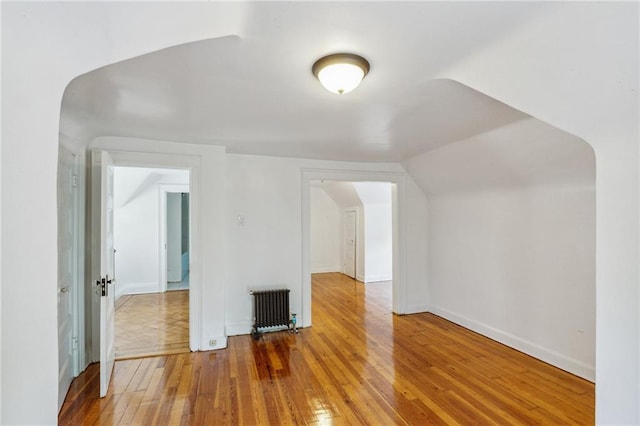 additional living space with radiator, baseboards, and hardwood / wood-style floors