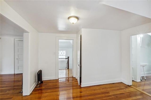 spare room with radiator heating unit and wood-type flooring