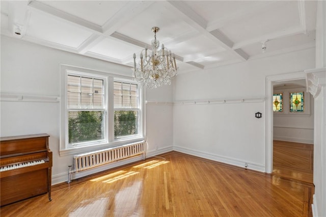 unfurnished dining area with radiator heating unit, coffered ceiling, beamed ceiling, and hardwood / wood-style floors