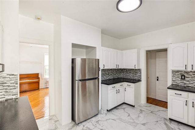 kitchen featuring freestanding refrigerator, white cabinetry, dark countertops, and tasteful backsplash