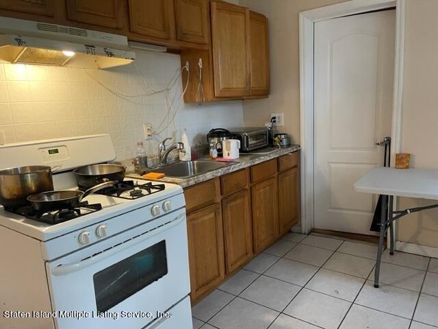 kitchen with white range with gas stovetop, sink, and light tile patterned floors