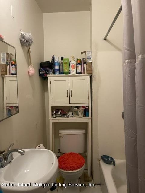 full bathroom featuring sink, shower / bath combination with curtain, and toilet