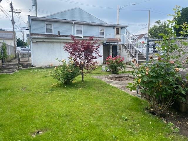 rear view of property with stairway, a yard, and fence