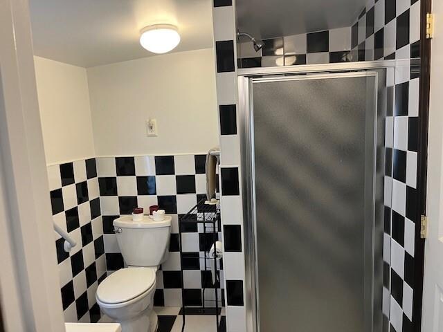 bathroom featuring tile walls, toilet, and walk in shower