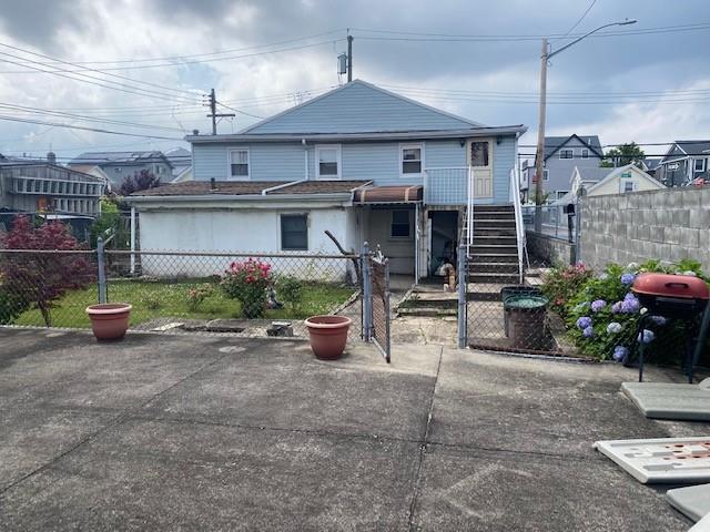 back of house with stairs, a fenced front yard, and a gate