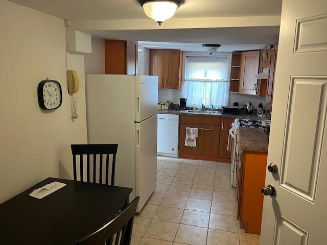 kitchen featuring white appliances, light tile patterned floors, dark countertops, a sink, and exhaust hood