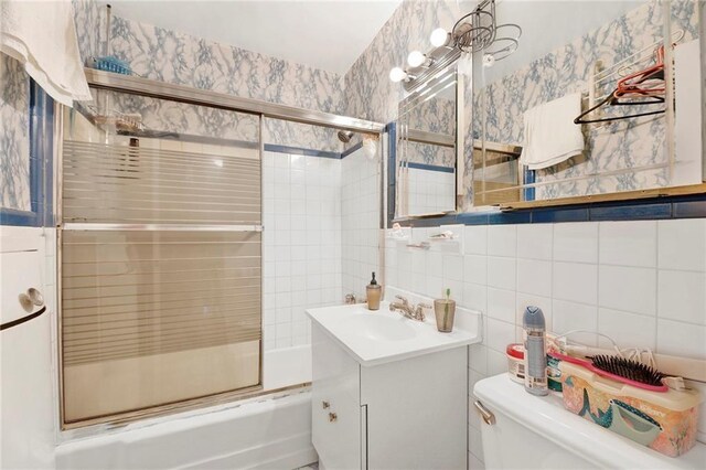 full bathroom featuring toilet, tasteful backsplash, shower / bath combination with glass door, tile walls, and vanity