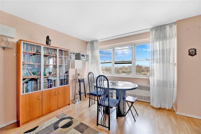 dining area featuring radiator, a wall unit AC, and light hardwood / wood-style floors