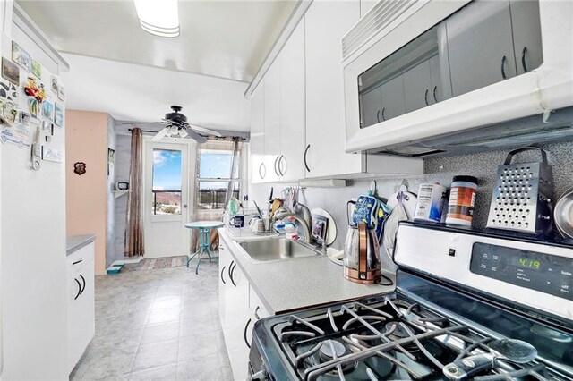 kitchen featuring sink, ceiling fan, range, white cabinetry, and backsplash