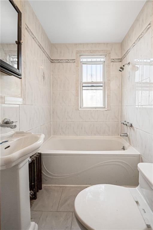 full bathroom featuring a sink, shower / bathing tub combination, tile walls, and toilet