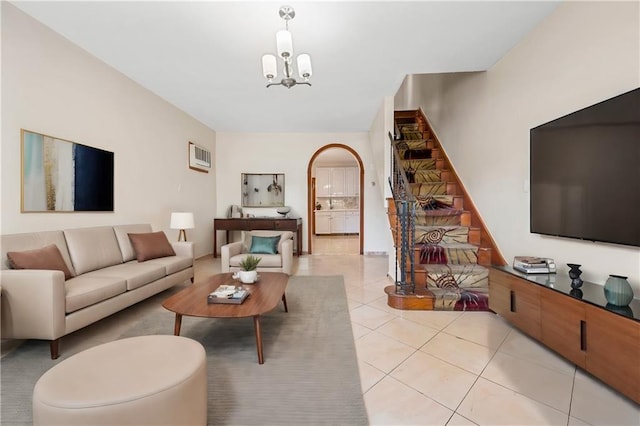 living area featuring light tile patterned floors, stairway, arched walkways, and a notable chandelier