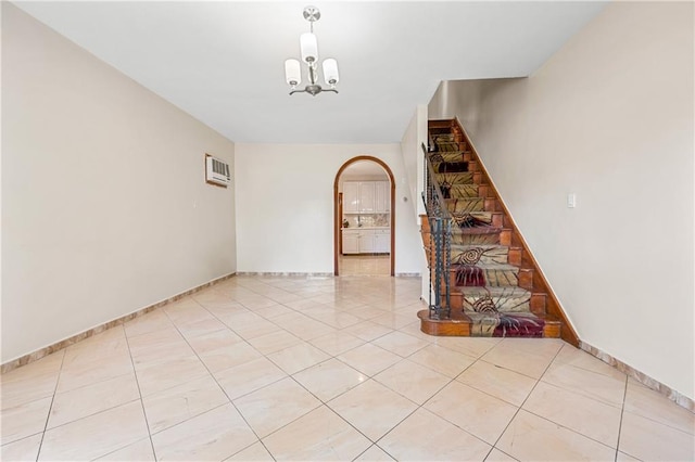 empty room with arched walkways, light tile patterned floors, baseboards, stairs, and an inviting chandelier