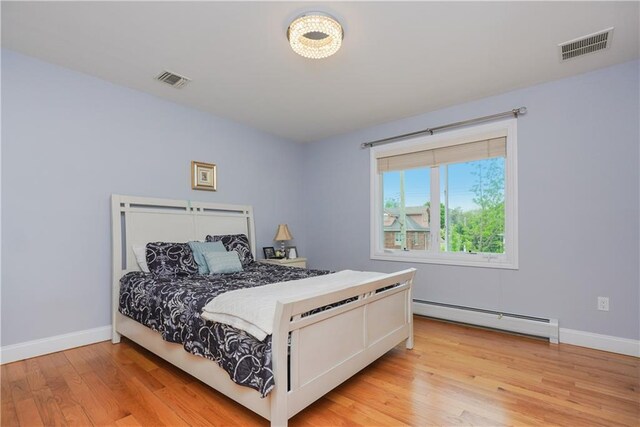 bedroom with light wood-type flooring and a baseboard radiator