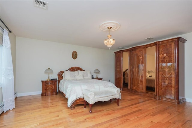 bedroom with an inviting chandelier, a baseboard radiator, and light wood-type flooring