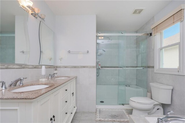 bathroom with a shower with shower door, tile walls, and toilet