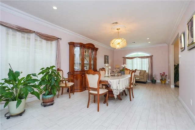 dining room featuring light hardwood / wood-style floors, ornamental molding, and an inviting chandelier