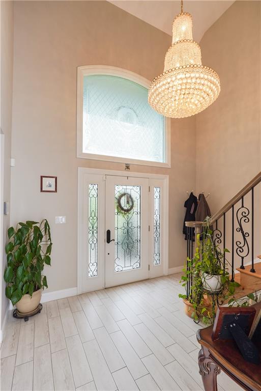 entryway with plenty of natural light, light hardwood / wood-style floors, a towering ceiling, and an inviting chandelier