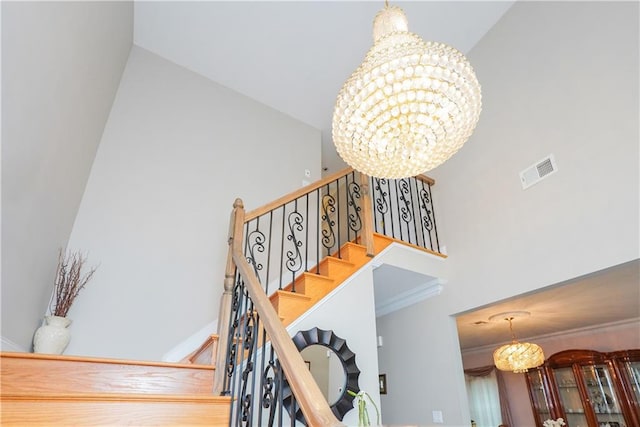 stairs featuring ornamental molding, a high ceiling, and a chandelier