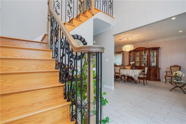 staircase with crown molding and a chandelier