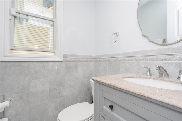 bathroom with vanity, tile walls, and toilet