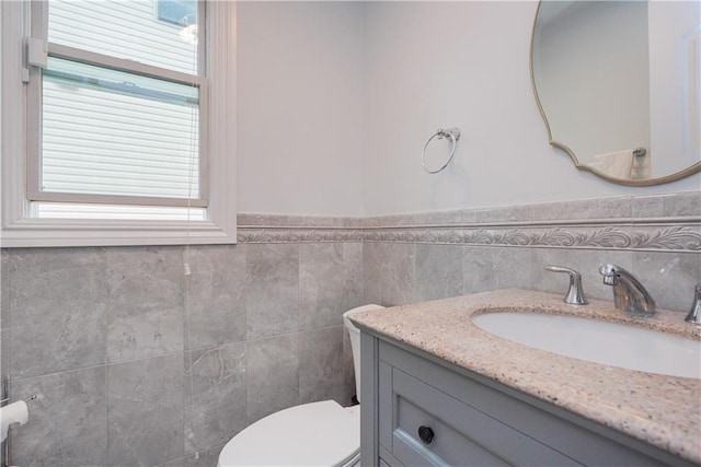 bathroom with vanity, tile walls, and toilet