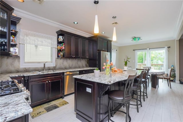 kitchen with decorative backsplash, appliances with stainless steel finishes, dark brown cabinets, sink, and a kitchen island