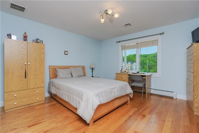 bedroom featuring light wood-type flooring and a baseboard radiator