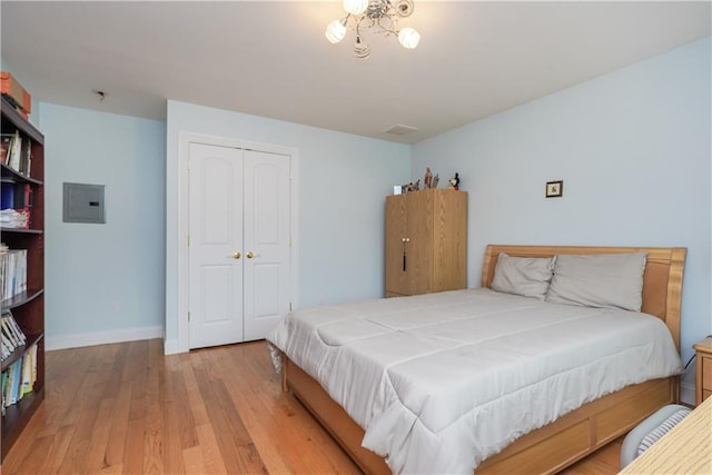 bedroom featuring light hardwood / wood-style flooring, electric panel, and a closet