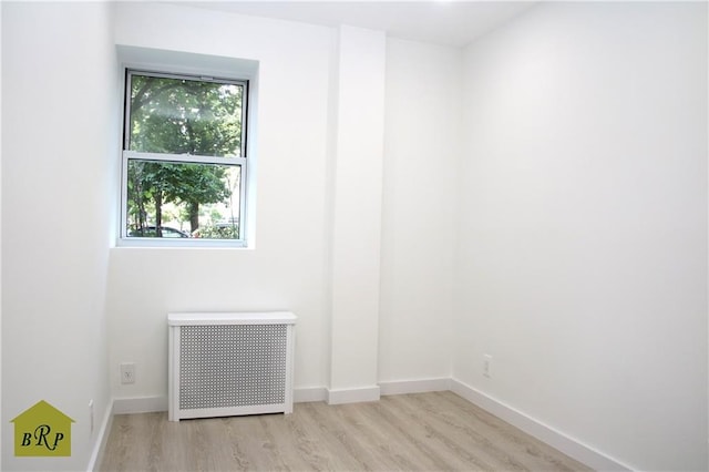 empty room featuring radiator heating unit and light hardwood / wood-style floors