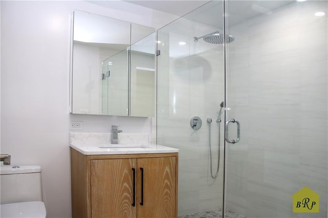 bathroom with vanity, a shower with shower door, and toilet