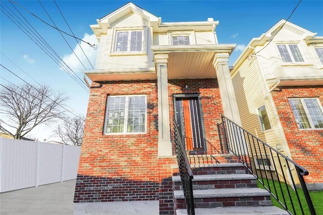 view of front facade with brick siding and fence