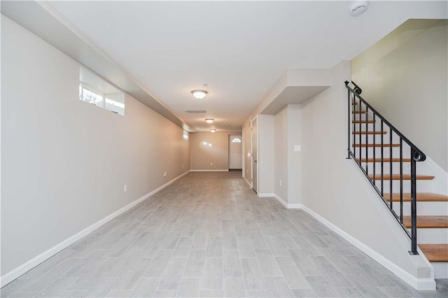 below grade area with stairs, light wood finished floors, visible vents, and baseboards