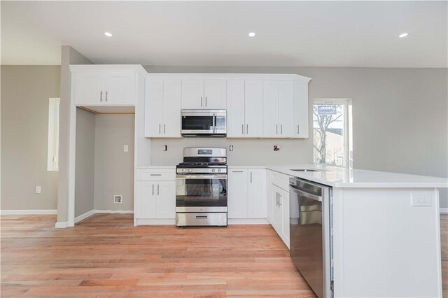 kitchen featuring white cabinetry, sink, light wood-type flooring, and appliances with stainless steel finishes