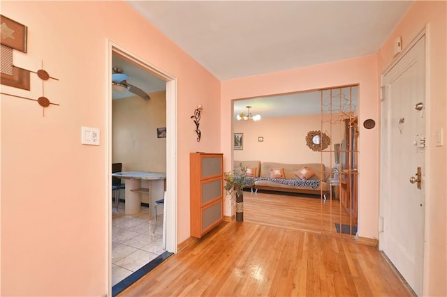 hall featuring light wood-type flooring and a chandelier