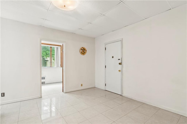 tiled spare room featuring a drop ceiling