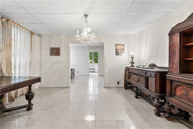 interior space with an inviting chandelier, a paneled ceiling, and light tile patterned floors