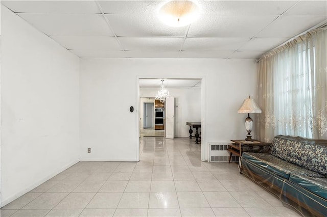 living room with a chandelier, a drop ceiling, and light tile patterned floors