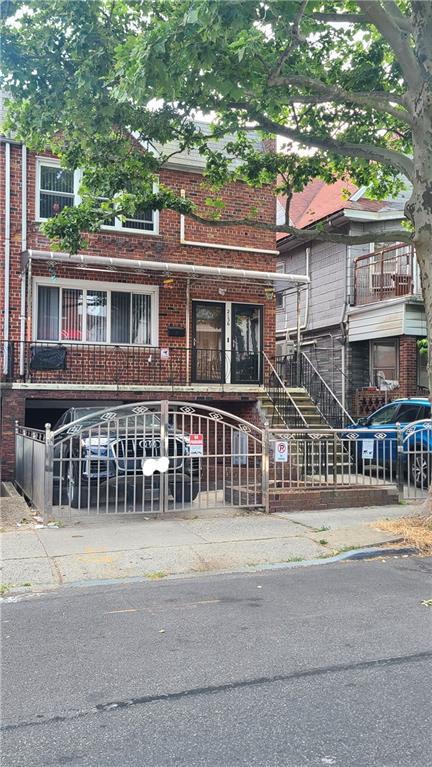 multi unit property featuring brick siding, a fenced front yard, and stairway
