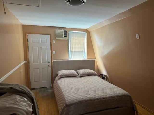 bedroom featuring an AC wall unit, wood-type flooring, and lofted ceiling