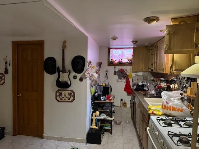 kitchen with gas range gas stove, under cabinet range hood, marble finish floor, and backsplash