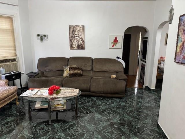 living area featuring arched walkways, marble finish floor, and cooling unit