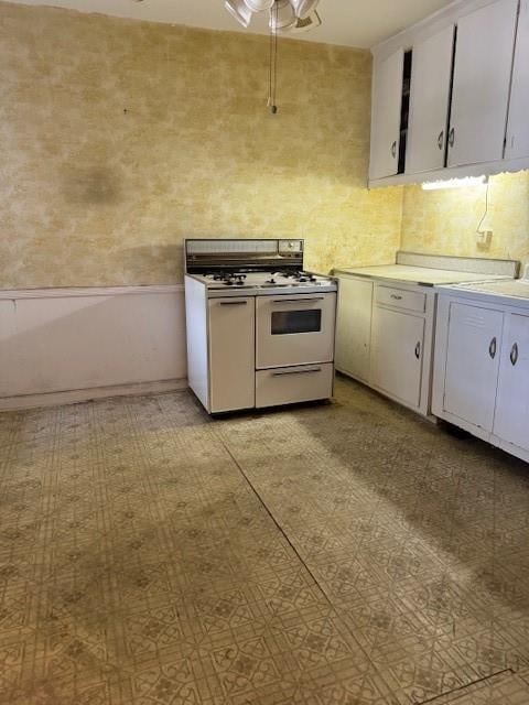 kitchen with white gas stove and white cabinets