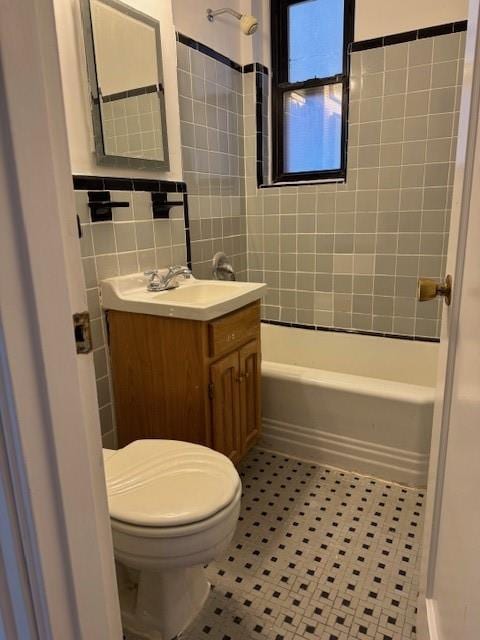 bathroom with toilet, shower / washtub combination, tile walls, tile patterned flooring, and vanity