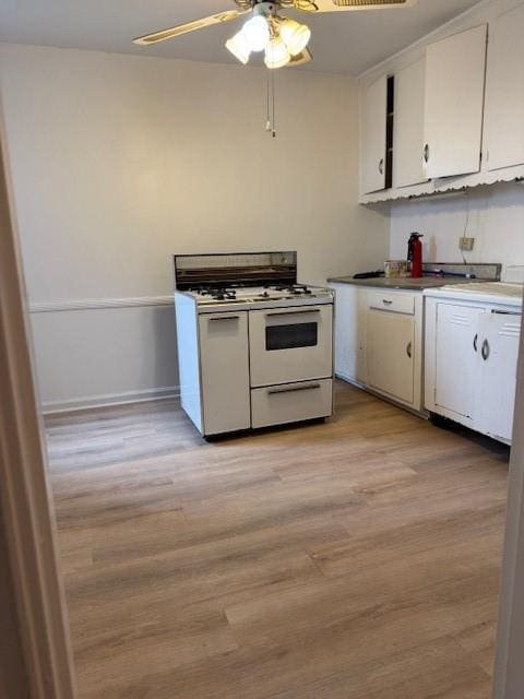 kitchen with ceiling fan, white cabinetry, light wood-style floors, and range with two ovens