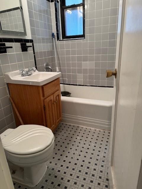 full bathroom with tile walls, tile patterned flooring, vanity, toilet, and tiled shower / bath