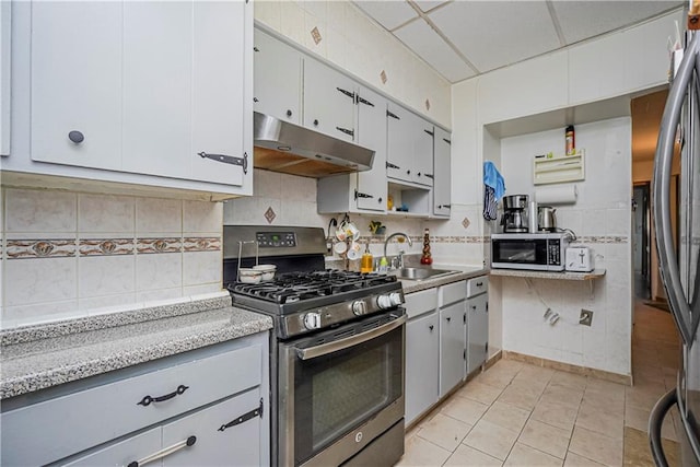 kitchen featuring sink, a paneled ceiling, stainless steel appliances, tasteful backsplash, and light tile patterned flooring