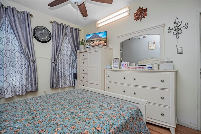 bedroom with ceiling fan, vaulted ceiling, and light hardwood / wood-style flooring