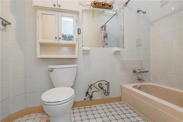 bathroom with tiled shower / bath, tile walls, and toilet