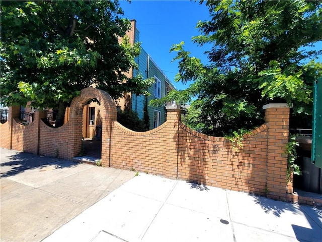 exterior space featuring brick siding, fence, and a gate